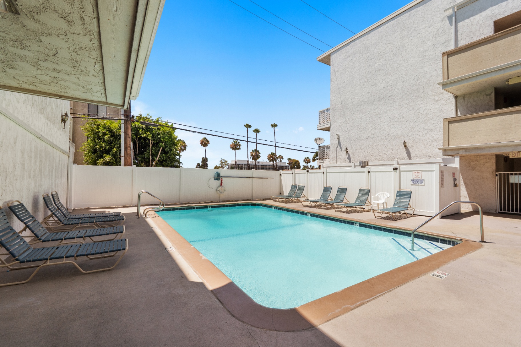 Private community pool with lounge chairs and palm trees